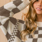 Woman wearing BiBi Checkered Contrast Chunky Sweater with bold checkered design and cozy knit.