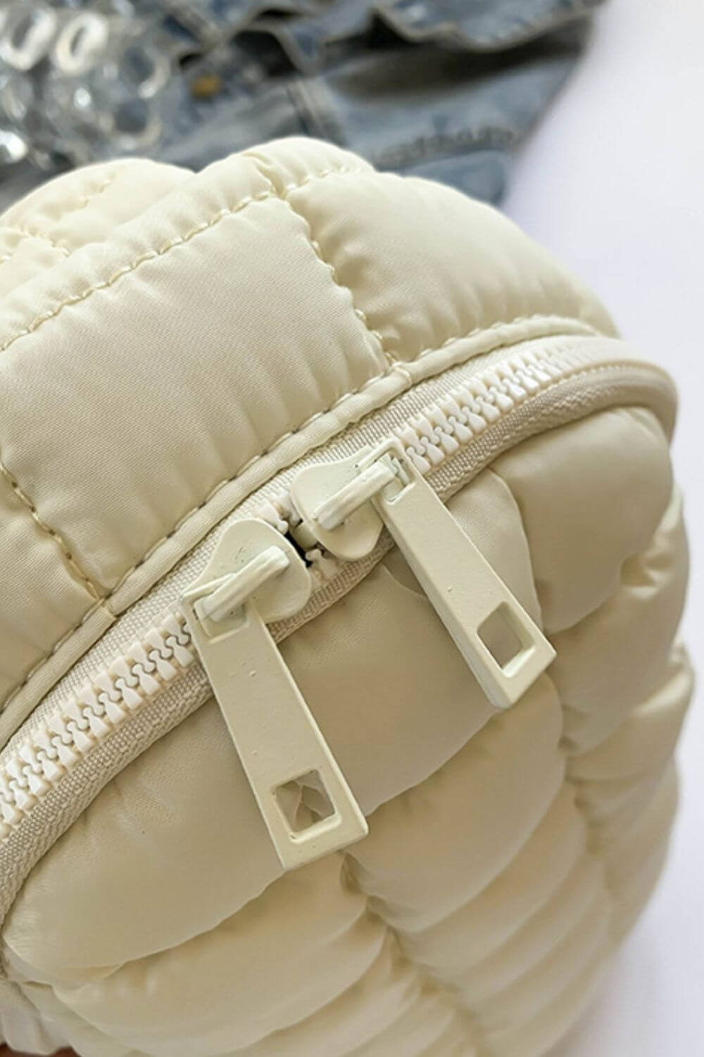 Close-up of cream Bella Road Quilted Nylon Crossbody Bag with durable zippers, perfect for fashion-forward adventures.