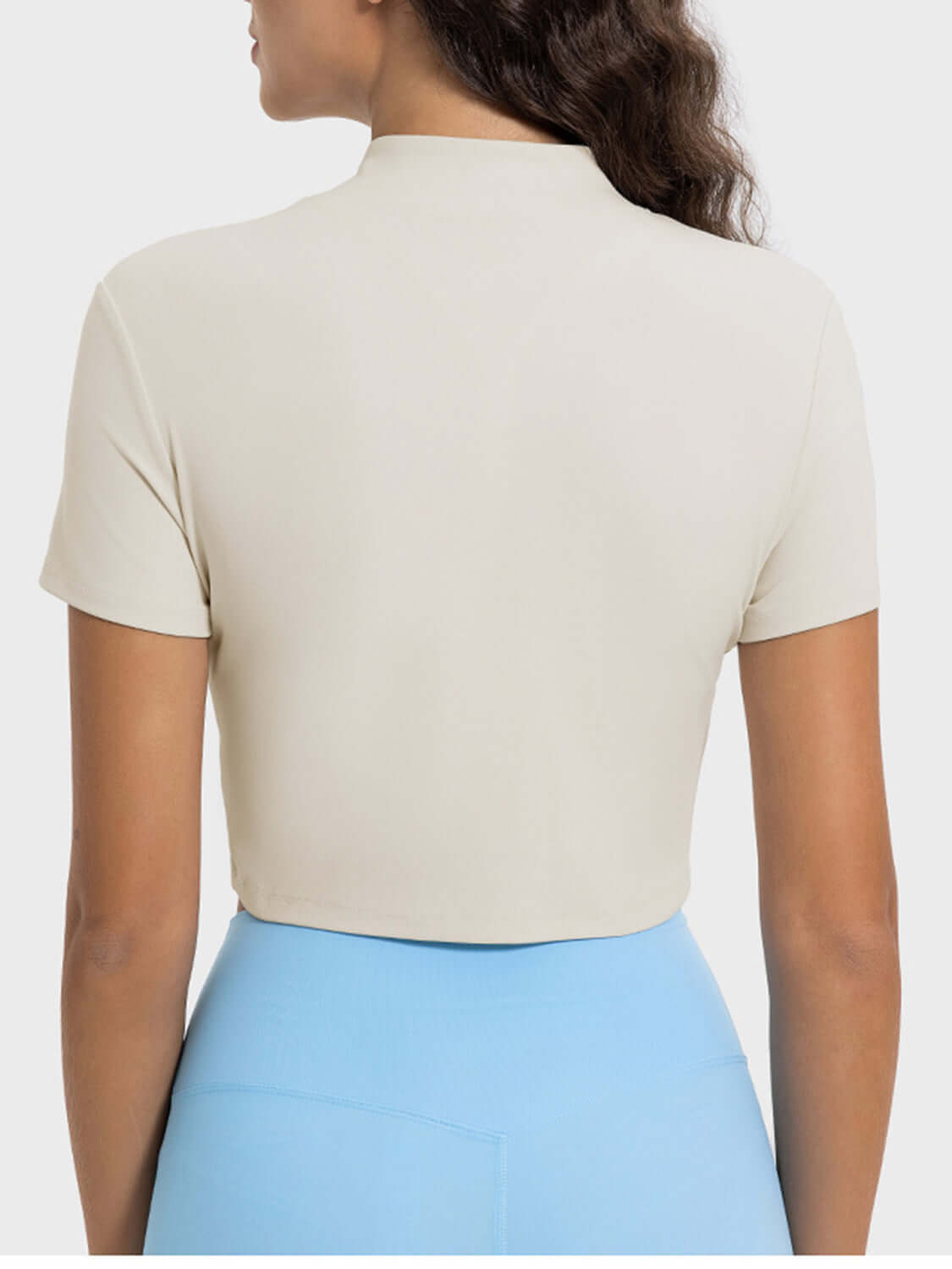 Back view of the Millennia Quarter Zip Short Sleeve Active T-Shirt in cream, showing short sleeves and a cropped style.