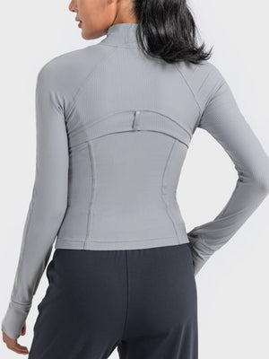 Back view of a woman wearing a gray Millennia Zip-Up Long Sleeve Sports Jacket, showcasing its sleek design and fit.