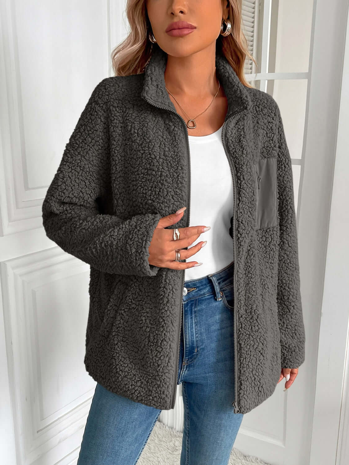 Woman wearing the Ivy Lane Zip Up Long Sleeve Fuzzy Jacket in monochrome, styled with jeans for a cozy and chic look.