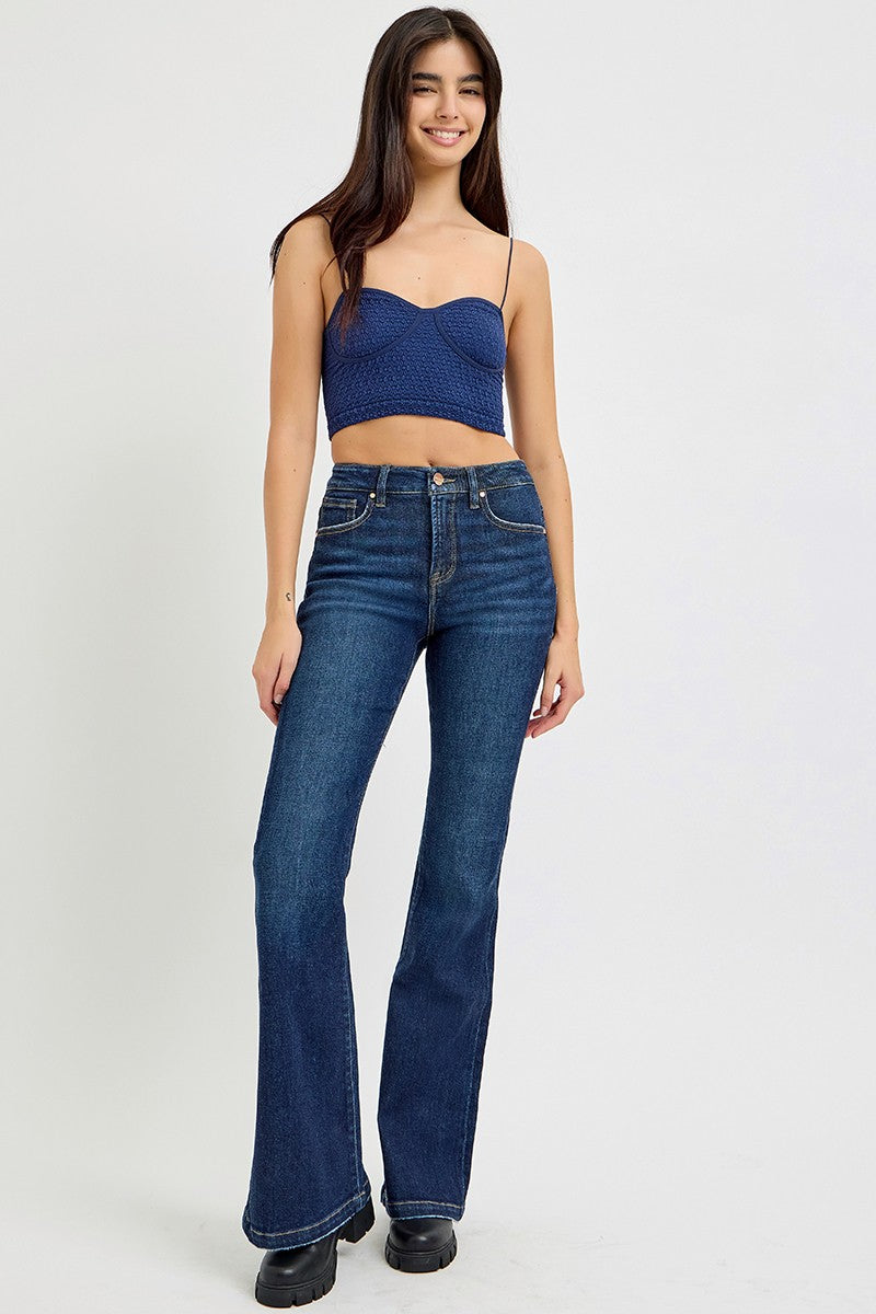 Person wearing RISEN full size high rise flare jeans with pockets, showcasing retro style with a chic blue top.