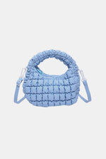 Light blue quilted puffy crossbody bag with removable strap, versatile for any occasion.