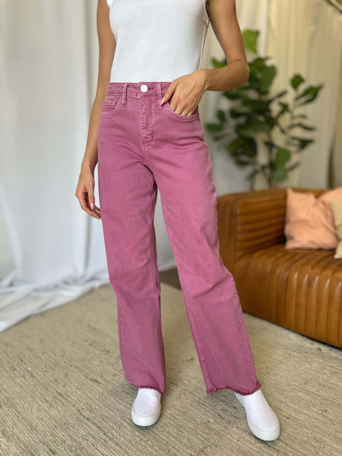 Woman wearing RFM Full Size High Rise Garment Dye Wide Leg Jeans in pink, paired with a white top and white sneakers.