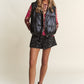 Stylish woman in J.NNA shiny metallic puffer vest with snaps and zippers for a trendy layered look.