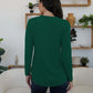 Woman wearing FAM-FAM round neck long sleeve t-shirt in green, standing with back to camera in stylish room with plants and shelves.