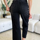 Woman wearing high waist black petite jeans with button fly and frayed hem by Judy Blue Jeans