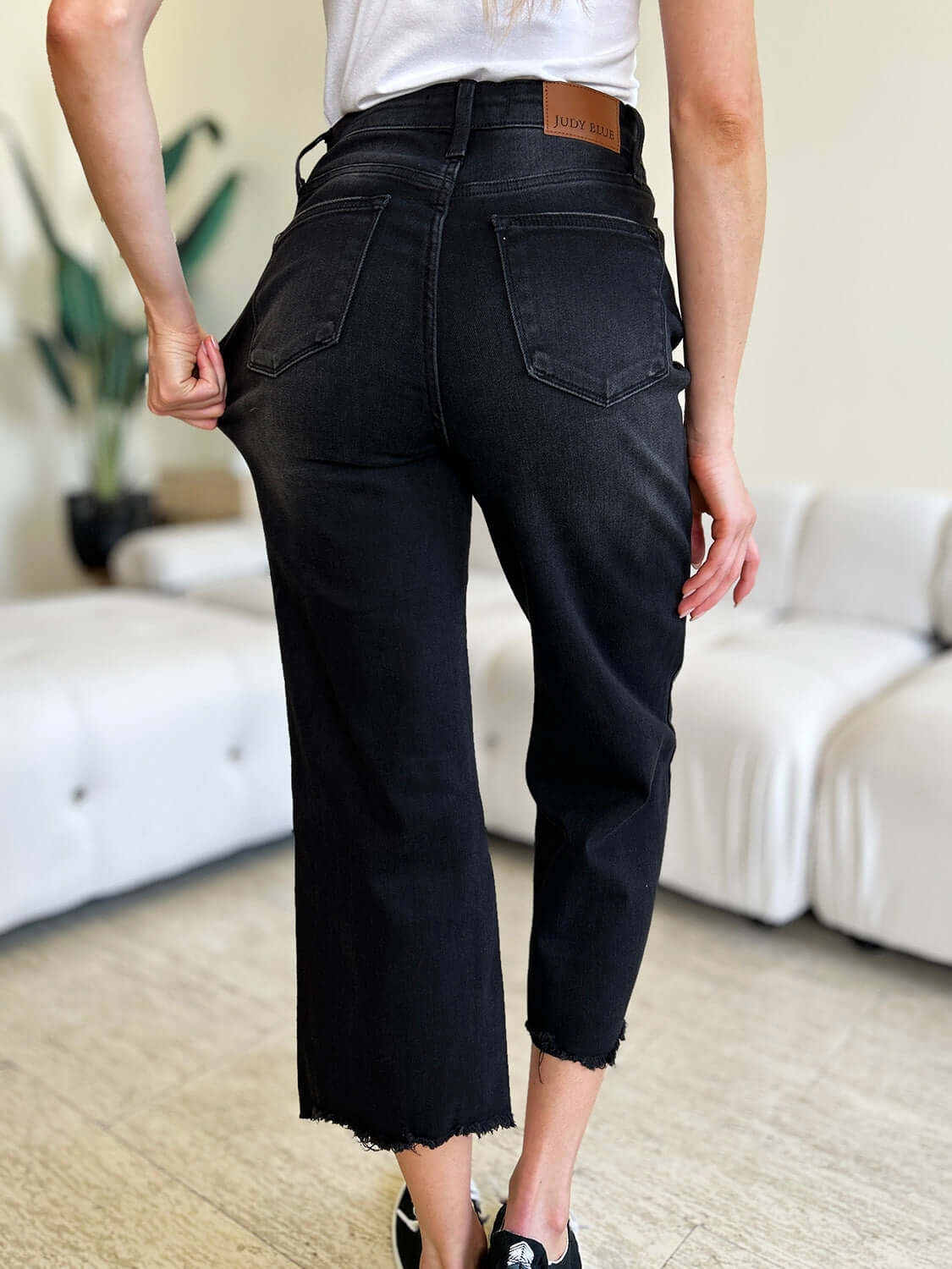 Woman wearing high waist black petite jeans with button fly and frayed hem by Judy Blue Jeans