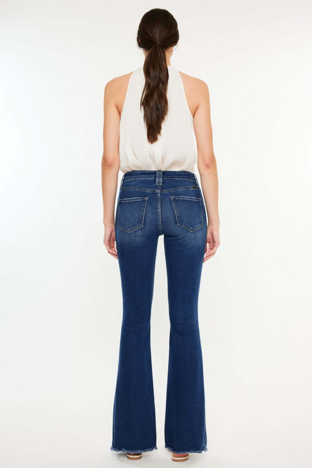 Woman wearing Cat's Whiskers Raw Hem Flare Jeans viewed from the back, showing the pocketed design and flare cut.