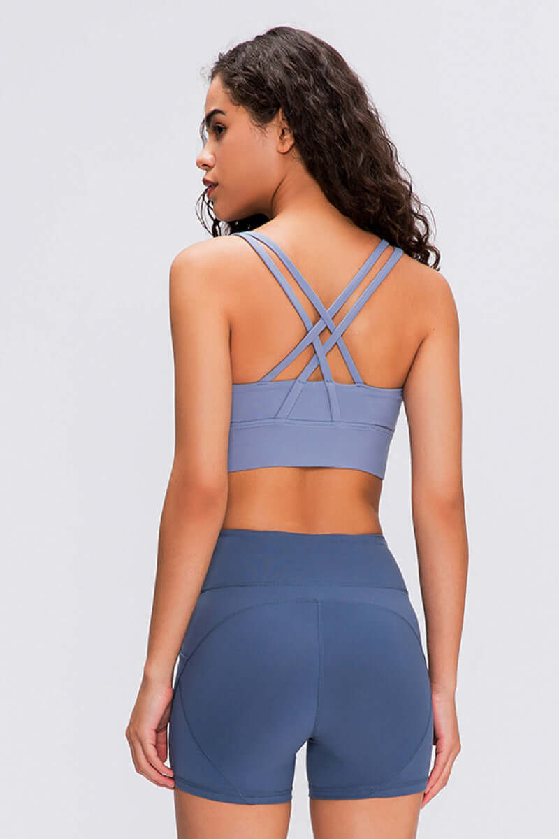 Woman in a blue Millennia Double X Sports Bra showcasing stylish double X strappy back and matching shorts.