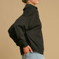 Woman wearing a black Johnny Collar Dropped Shoulder Sweatshirt, showcasing a relaxed fit and modern style with stylish jeans.