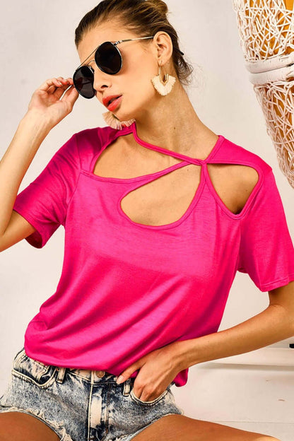 Woman wearing a Cutout Asymmetrical Neck Short Sleeve T-Shirt in bright pink, paired with denim shorts and sunglasses.