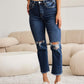 Woman wearing RFM Jeans Crop Dylan Full Size Tummy Control Distressed High Waist Raw Hem Jeans in living room.