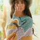 Woman in a stylish BiBi wavy hem sweater with openwork detailing and a grey hat, showcasing a vibrant contrast design.