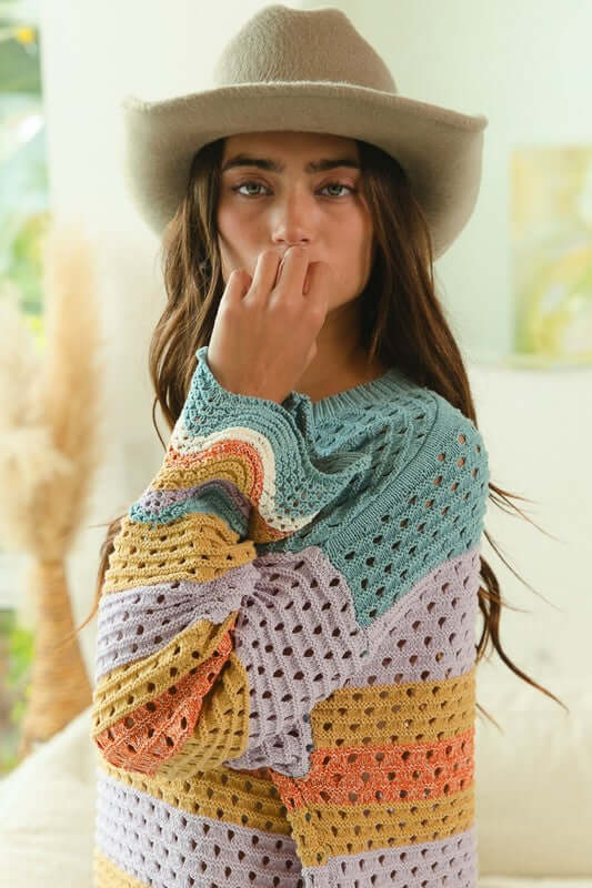 Woman in a stylish BiBi wavy hem sweater with openwork detailing and a grey hat, showcasing a vibrant contrast design.