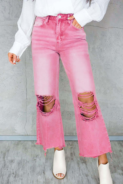 Woman wearing pink distressed raw hem jeans with pockets, featuring ripped knees and a casual, trendy look.