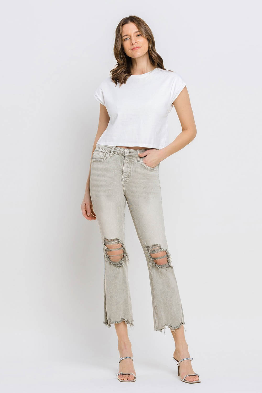 Woman wearing Lovervet distressed raw hem cropped flare jeans with a white t-shirt and heels showcasing trendy urban style.