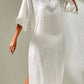 Woman wearing a white slit V-neck flounce sleeve cover-up dress made of sheer polyester.