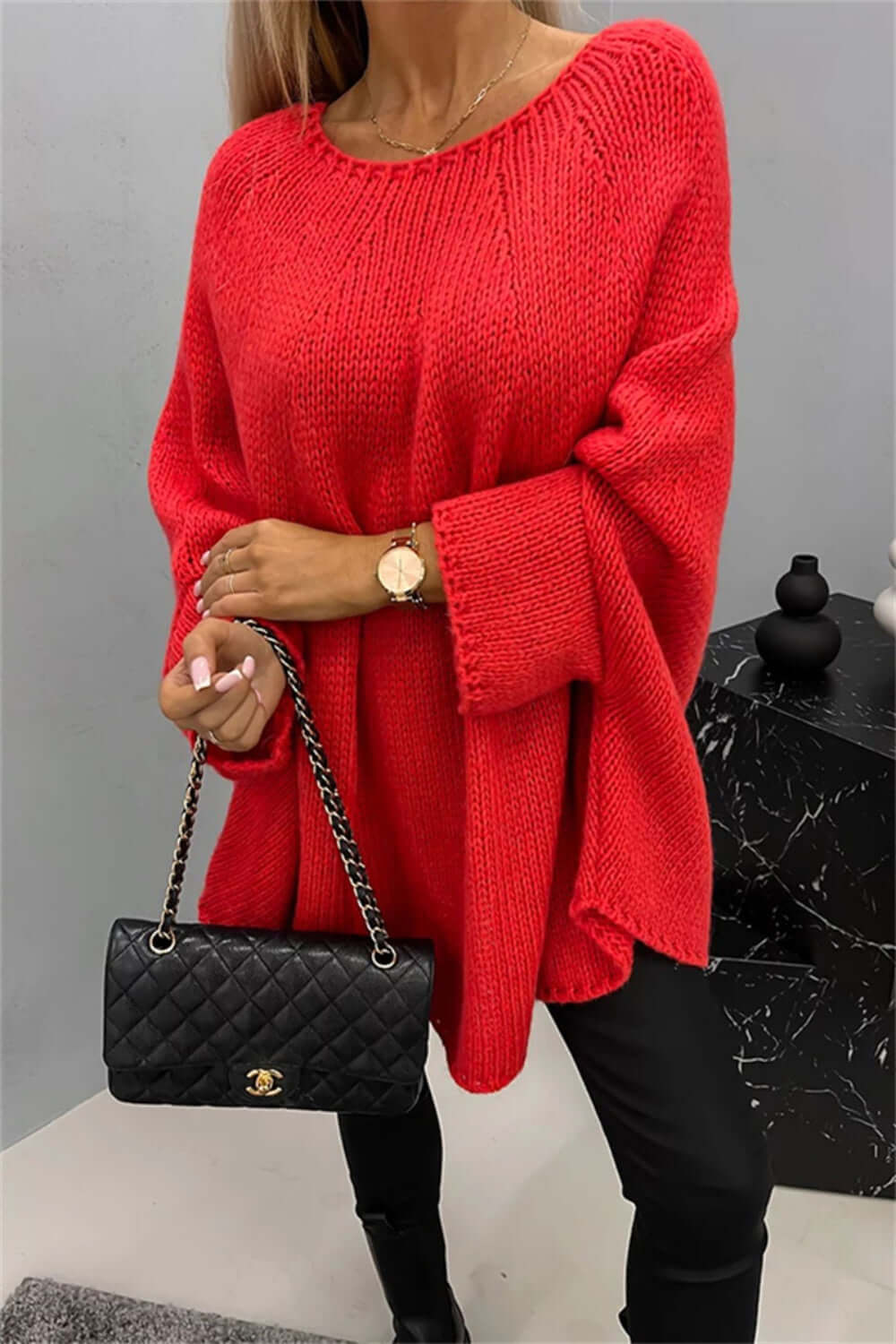 Woman wearing cozy Bella Road Round Neck Batwing Sleeve Sweater in vibrant red, holding a stylish black quilted handbag.