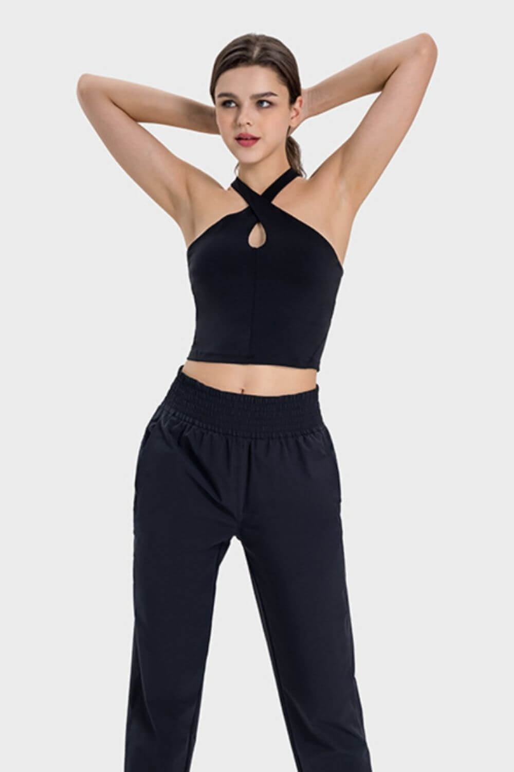 Stylish model showcasing the Millennia Crisscross Grecian Neck Active Cami paired with comfy black pants. Perfect for workouts!