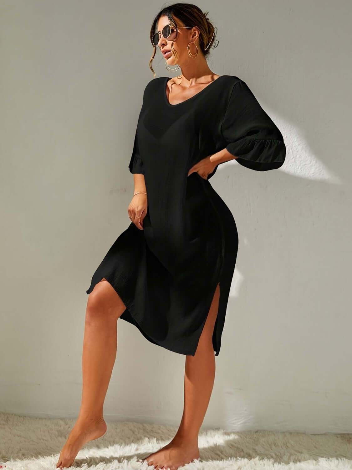 Woman wearing a black slit V-neck flounce sleeve cover-up, backless and sheer with no stretch, made of 100% polyester.