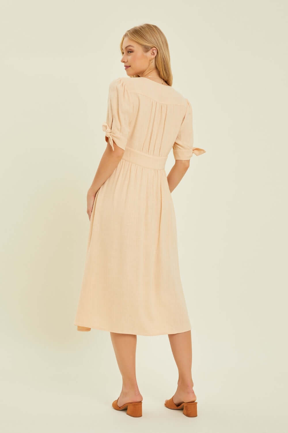 Woman wearing HEYSON Textured Linen V-Neck Button-Down Midi Dress, showing back detail, elegant and airy for warm weather occasions.