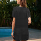 Woman wearing Bella Road Swim Openwork cover-up in black, standing poolside against a lush tropical backdrop.