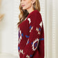 Woman wearing HEYSON Full Size Aztec Soft Fuzzy Sweater in red, featuring a vibrant Aztec pattern, standing in a bright room.