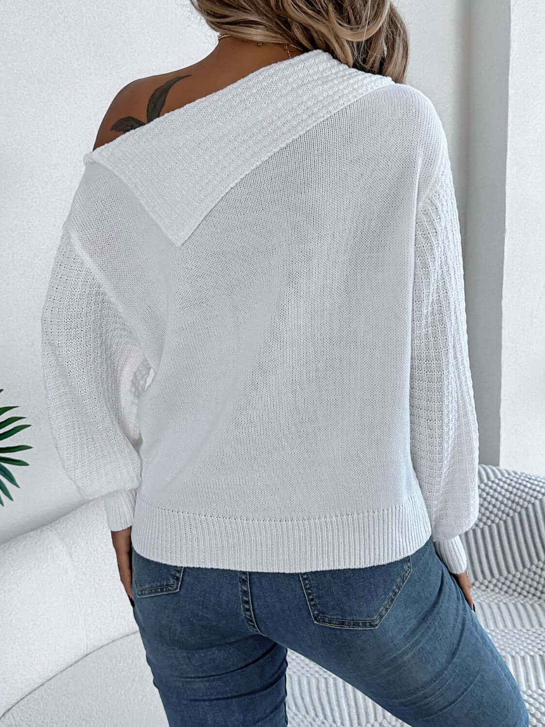 Woman wearing Bella Road Cable-Knit One Shoulder Long Sleeve Sweater in white, showcasing back view and unique one-shoulder design.