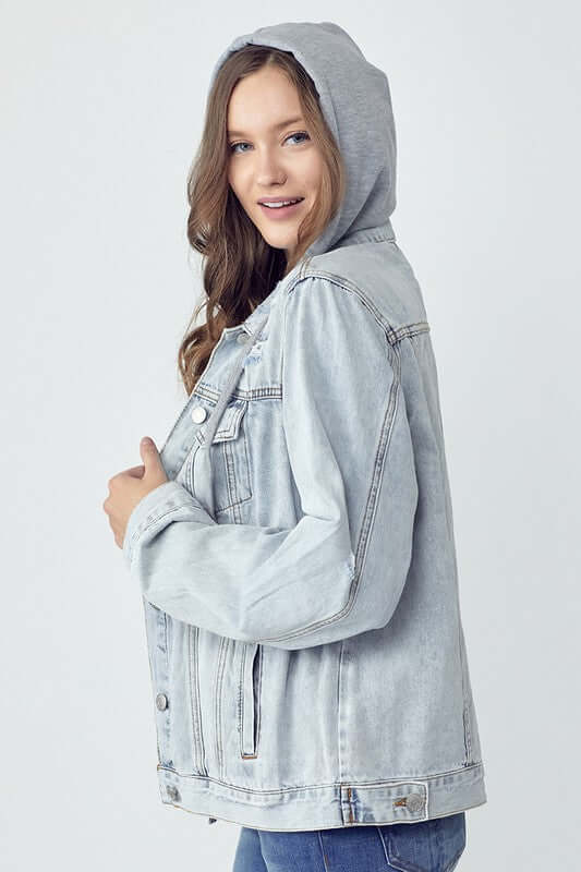 Young woman wearing a distressed denim jacket with a drawstring hood, showcasing a casual and stylish look.