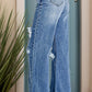 Woman wearing distressed high waist bootcut jeans with slightly stretchy material, perfect for a trendy and comfortable look.