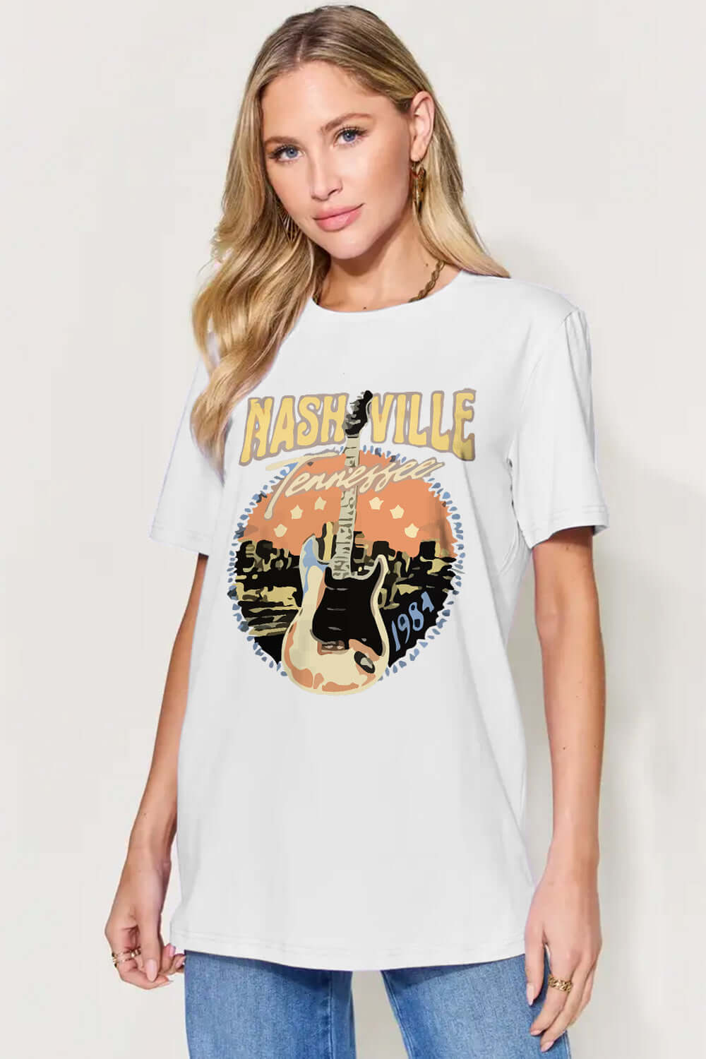 Woman wearing Graphic Round Neck Short Sleeve T-Shirt with Nashville design and guitar print in white, casual style.