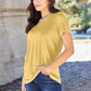 Woman wearing Basic Bae Bamboo Full Size V-Neck Short Sleeve T-Shirt in yellow, standing outdoors near a stone wall.