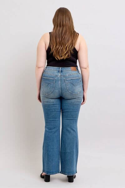 Woman showcasing Judy Blue mid rise tummy control vintage wash jeans from the back, highlighting the retro style and fit.