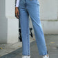 Light wash side slit high waist straight jeans styled casually with white sneakers on a trendy city street.