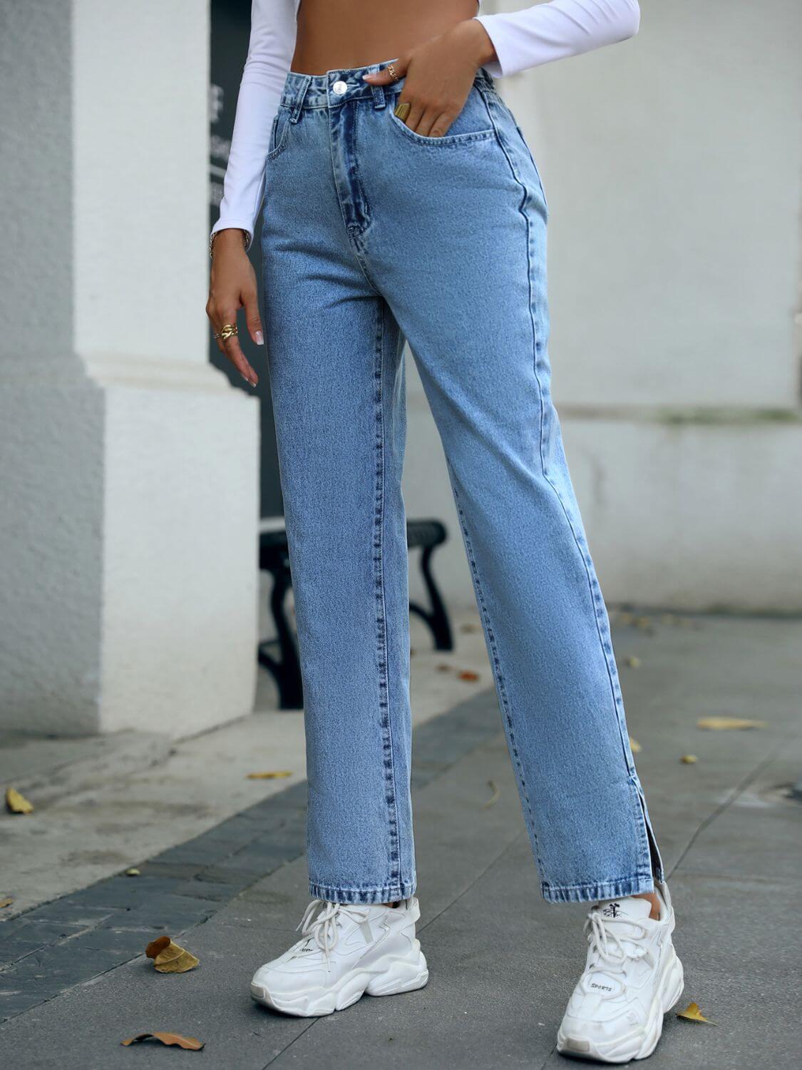 Light wash side slit high waist straight jeans styled casually with white sneakers on a trendy city street.