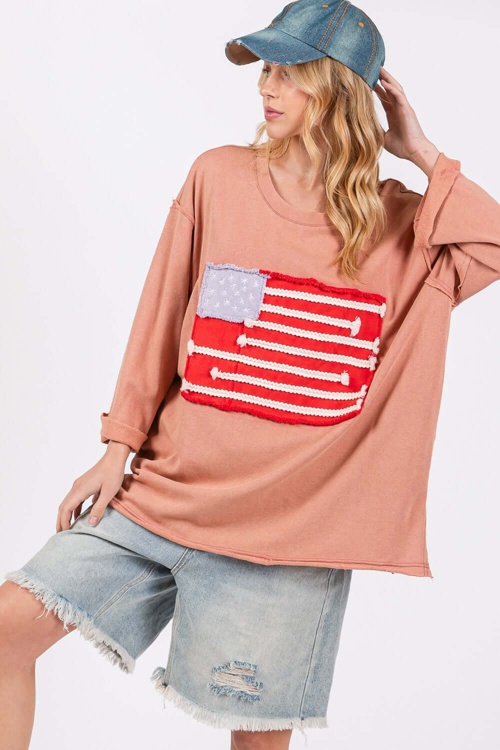 Woman wearing Full Size American Flag Patch Drop Shoulder T-Shirt with denim shorts and cap