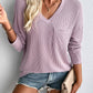 Woman wearing Double Take Pocketed Textured V-Neck Long Sleeve T-Shirt in lavender color paired with denim shorts and accessories.