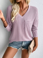 Woman wearing Double Take Pocketed Textured V-Neck Long Sleeve T-Shirt in lavender color paired with denim shorts and accessories.