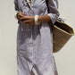 Woman wearing Bella Road Tied Button Up Three-Quarter Sleeve Dress, holding a woven straw bag, showcasing casual and chic fashion style.