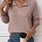 Woman wearing a striped half zip long sleeve t-shirt, holding a coffee cup.