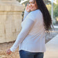 Smiling model wearing a round neck long sleeve t-shirt in white, paired with blue jeans, standing outdoors.