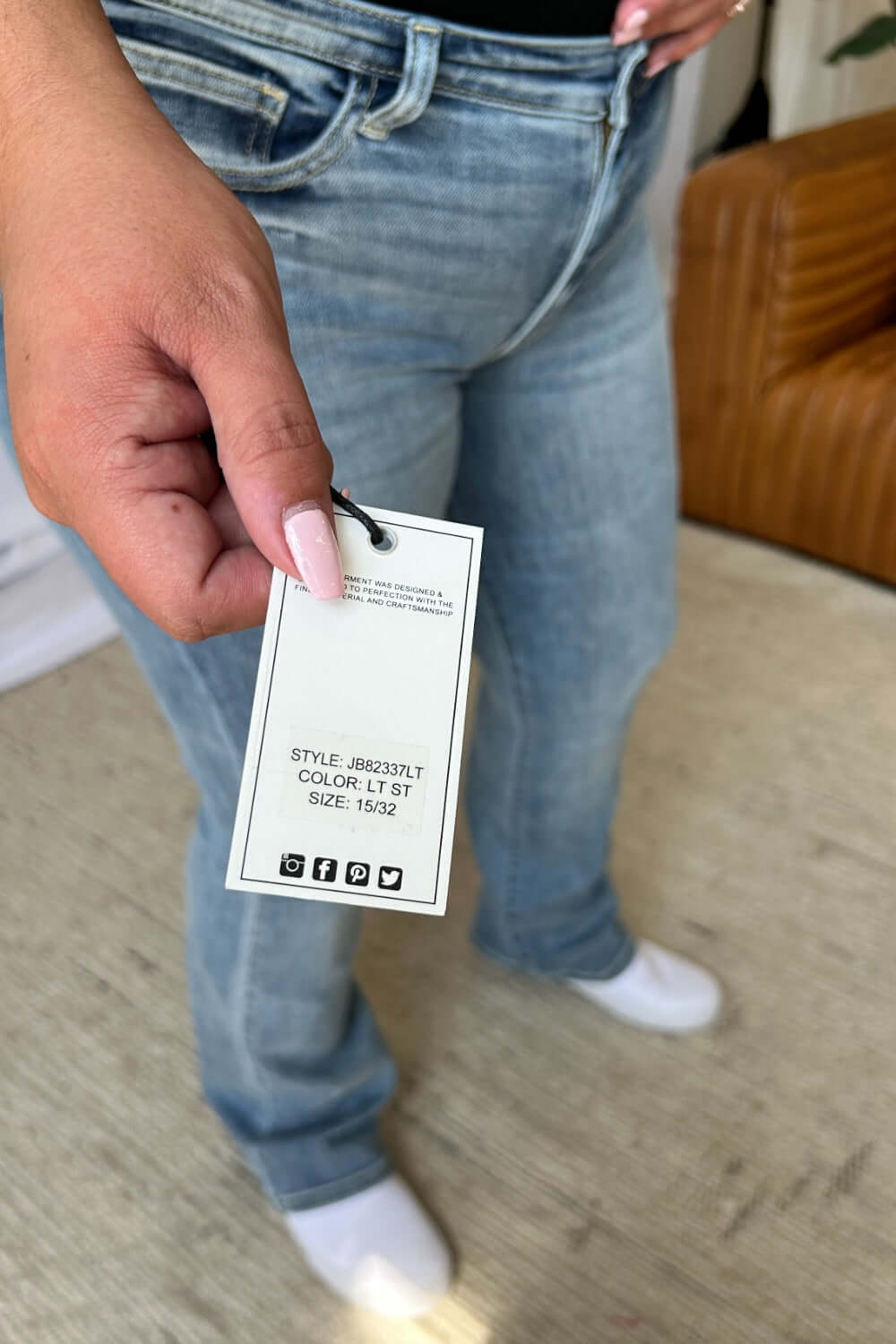 Woman holding tag on Judy Blue medium rise bootcut jeans, showcasing classic blue denim style and comfortable fit.