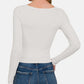 Woman wearing scoop neck long sleeve t-shirt in white, back view, paired with blue jeans.