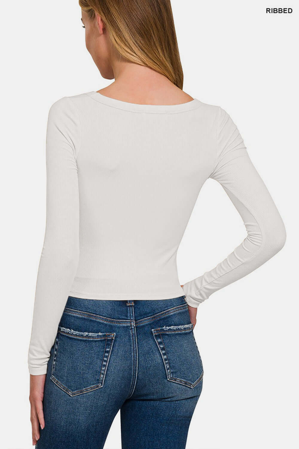 Woman wearing scoop neck long sleeve t-shirt in white, back view, paired with blue jeans.