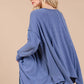 Woman wearing Ces Femme asymmetrical long sleeve top in blue, showcasing a relaxed fit with a hi-low hem and drop sleeves.