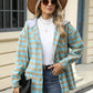 Woman wearing a Bella Road Drawstring Plaid Long Sleeve Hooded Jacket in blue and beige, accessorized with a hat, sunglasses, and a black purse.