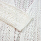 Close-up of a cream openwork open front dropped shoulder cardigan made of acrylic and cotton.