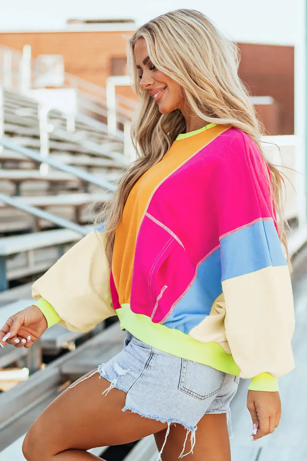 Woman wearing Bella Road Color Block Round Neck Long Sleeve Top with vibrant blocks of pink, yellow, blue, and beige.