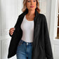 Woman wearing black Ivy Lane fuzzy jacket, open over white top, paired with jeans, showcasing cozy and stylish fashion.